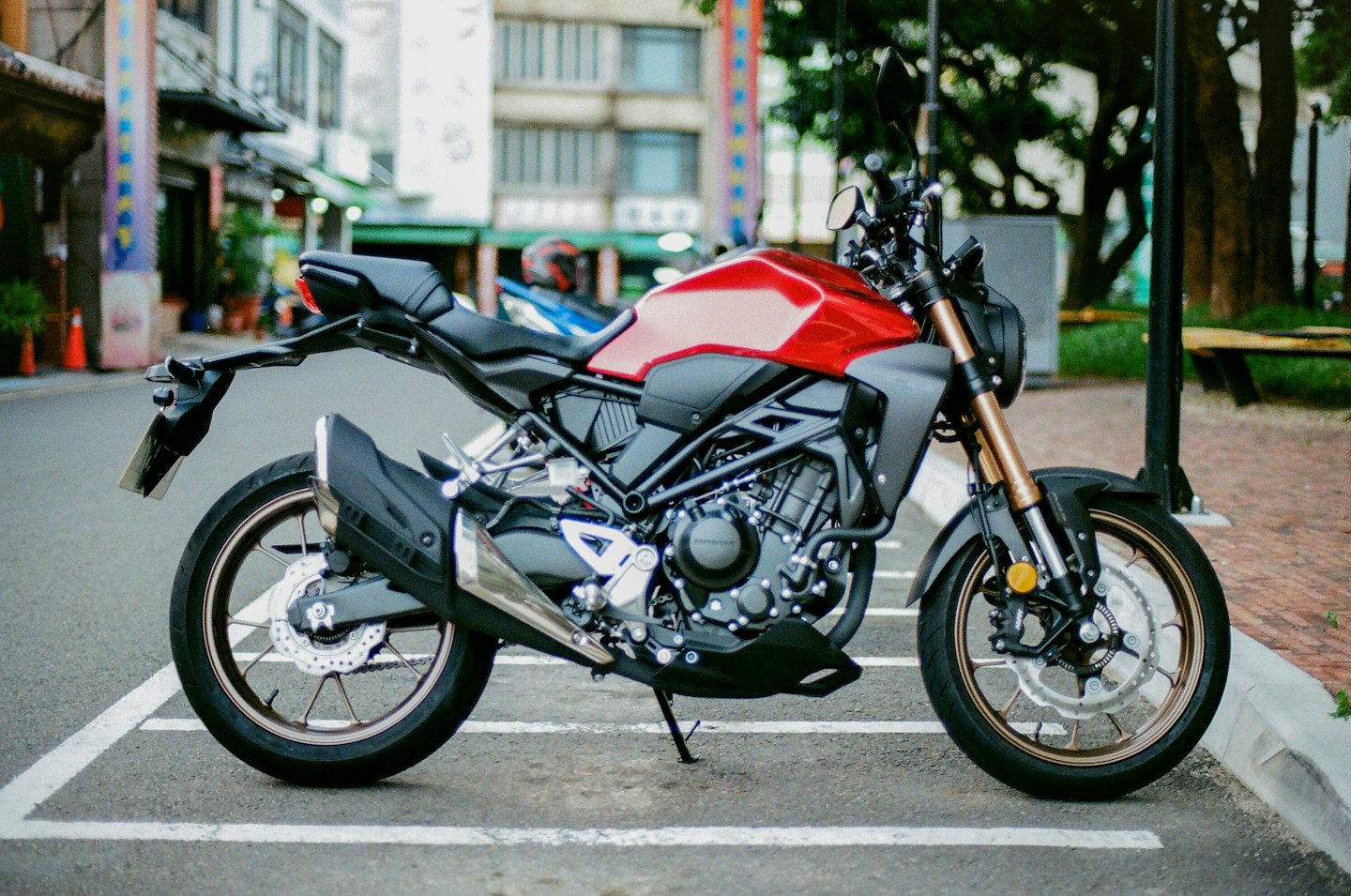 A red and black motorcycle parked on a city street.